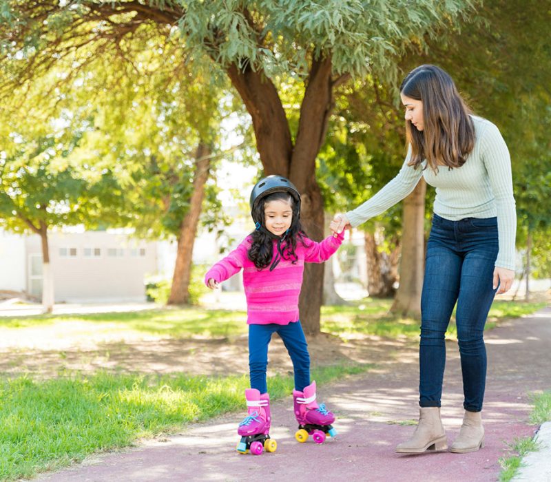 Mom teaching girl how to roller skate